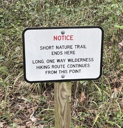 Trail sign that says "long, one way wilderness hiking route continues from this point"